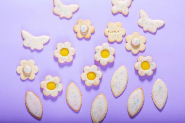 Limonlu kurabiyeler kelebek, çiçek ve yaprak şeklinde. Leylak arkaplan, bahar ya da yaz kompozisyonu üzerine jöleli ve renkli şekerle kaplanmış kurabiyeler..