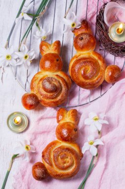 Tavşanlardan, boyanmış yumurtalardan ve bahar buketlerinden oluşan paskalya kompozisyonu. Eflatun arkaplanda maya hamurundan bir demet, kırsal stil, seçici odak.