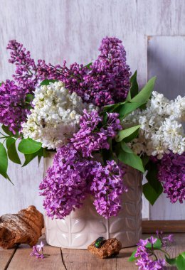 Açık arkaplanda bir buket leylak, odun parçaları ve böcekler. Bahar aylarında ahşap bir masanın üzerindeki leylak buketi gibi, kırsal tarzda, seçici bir odak noktası..