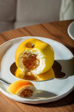 Şeftali dolgulu kremalı pasta kadife jöleli ve bir kafedeki masada bir fincan latte. Tatlı, içki, bir kafede ahşap masa, seçici bir odak..