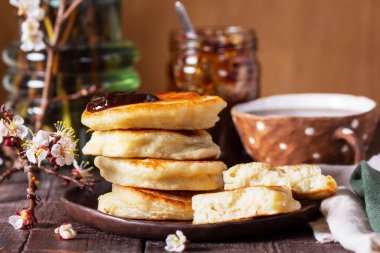 Erik reçeli ve çaylı maya krepleri ve ahşap bir masanın üzerinde çiçek açan kayısı dalları. Kırsal biçim, seçici odak.