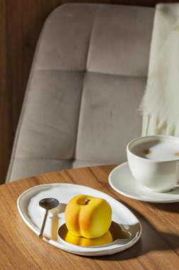 Şeftali dolgulu kremalı pasta kadife jöleli ve bir kafedeki masada bir fincan latte. Tatlı, içki, bir kafede ahşap masa, seçici bir odak..