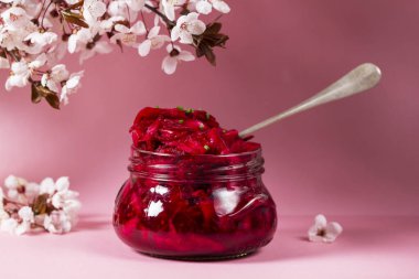 Pancar, biberiye, hardal ve diğer baharatlarla birlikte salamura lahana ve erik çiçeği. Lahana turşulu cam kavanoz, pembe arka planda çiçek açan erik dalları. Seçici odak.