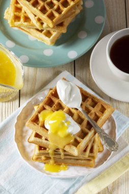 Kremalı ve limonlu Belçika waffleları, çay ile servis edilir. Karnaval için geleneksel bir ikram. Hafif arka planda kremalı waffle kahvaltısı, köy tarzı..