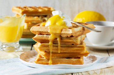 Kremalı ve limonlu Belçika waffleları, çay ile servis edilir. Karnaval için geleneksel bir ikram. Hafif arka planda kremalı waffle kahvaltısı, köy tarzı..
