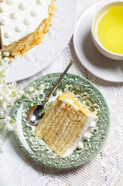 Badem yaprakları ve mumlarla süslenmiş ince katmanlardan yapılmış ekşi krema ve ballı pasta. Kutlama pastası, bir fincan nane çayı, bir buket vadi zambağı ve arka planda mumlar. Kırsal biçim.