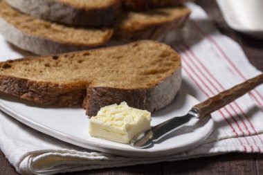 Hafif arka planda tereyağlı ev yapımı zanaatkar ekmeği. Tam tahıllı ve çavdar ekmekli tereyağlı ev şeklinde, köy usulü..