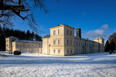 State Classicist chateau Kynzvart in winter under snow and with blue sky - castle is located near the famous west Bohemian spa town Marianske Lazne (Marienbad) - Czech Republic