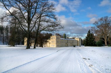 State Classicist chateau Kynzvart in winter under snow and with blue sky - castle is located near the famous west Bohemian spa town Marianske Lazne (Marienbad) - Czech Republic