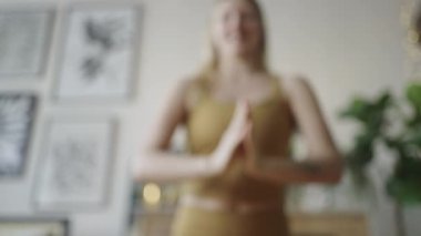 Athletic woman doing yoga on a mat at home, stretching her fingertips forward, spiritual development and meditation in a harmonious environment.