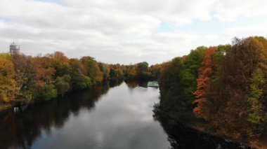 Aerial view of autumn city park with yellow and red trees and boat station with wooden rowing pleasure boats on the lake
