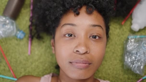 African American Woman Lies Fluffy Green Rug Scattered Plastic Rubbish — Video Stock