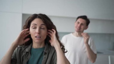 Curly-haired woman plugs ears in stress not wanting to hear angry husband quarrel shout and argue about family problems closeup