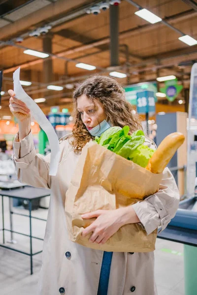 Молодая Женщина Неприятно Удивлена Глядя Бумажный Чек Продуктовом Супермаркете Держа — стоковое фото