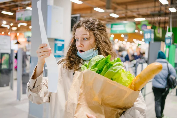 Молода Жінка Медичній Масці Виглядає Шоковано Паперовій Перевірці Продуктовому Супермаркеті — стокове фото
