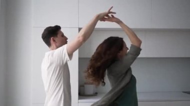 Aşık evli bir çift, parlak mutfakta güçlü bir şekilde dans eder, sarılır ve öper, kadın döner ve kocasının kollarına düşer..