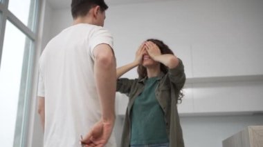 Brunet husband surprises young wife with curly hair giving woman key with house key-chain to new apartment happy lady hugs and kisses man