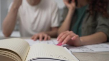 Young happy married couple discussing renovations in a new apartment and making notes in a paper notebook