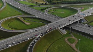 Şehir dışındaki yeşil çayırlar arasında giden otomobillerle çok katlı trafik üst geçidi kavşağı havadan panorama