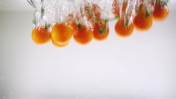 Pomidory Wiśniowe Gałązce Wpadają Wody Białym Tle Tworząc Pęcherzyki Powietrza — Wideo stockowe