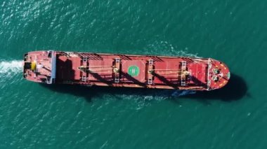 Denizde yüzen ve kargo taşıyan büyük bir deniz gemisinin hava görüntüsü.