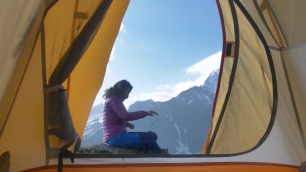 フリーランサーは山のラップトップの後ろでリモートワークを開始し 女性はコンピュータを開き 美しい場所でストレッチ彼女の腕を伸ばし ハイキングのテントからの眺め 屋外のリモートワーク — ストック動画