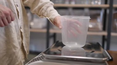 Kadın, sıfır atık paketlemeden ürünleri sıfır ve doğru bir şekilde tartmak için konteynırını ölçeğe koyuyor. Bilinçli tüketim, self-servis, atık azaltma ve çevre yardımı