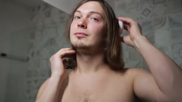 髪の長い男と髭は鏡の前のシャワーで彼の髪を組み合わせる クローズアップ肖像画 — ストック動画
