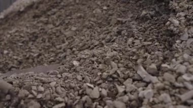 İşçi, küçük gevşek taşlar yığınından çıkan bir kürekle moloz kazıyor. İnşaat kırıntısı yavaş çekim