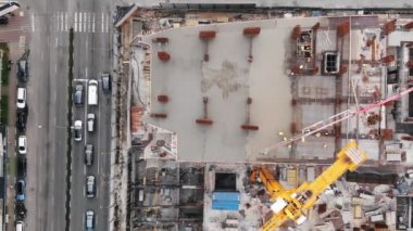 İnşaat vinçleri olan bir inşaat alanının yukarıdan aşağı manzarası. İşçiler çok katlı binaların beton ve monolitik yapısını dökerler.