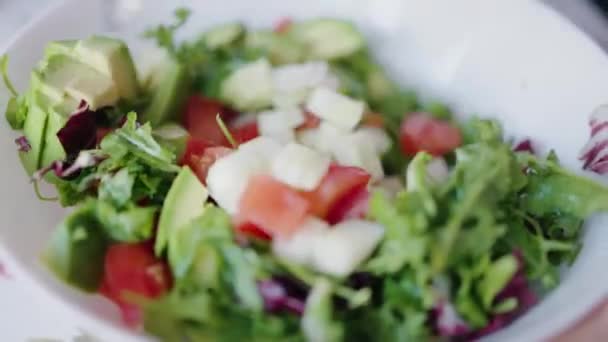 烹调蔬菜沙拉 鳄梨和青菜 用勺子在白盘中搅拌 西红柿 黄瓜和青菜根茎沙拉 健康食品 — 图库视频影像