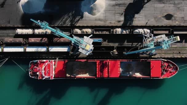港内の船舶から鉱物肥料や砕石を陸揚げする港湾クレーンのトップダウンビュー — ストック動画