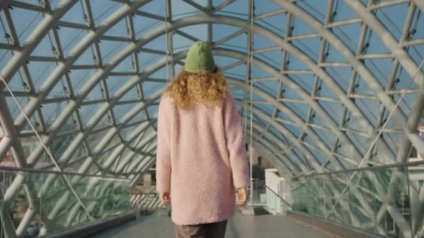 Mujer Abrigo Piel Rosa Camina Largo Moderno Puente Cristal Futurista — Vídeo de stock