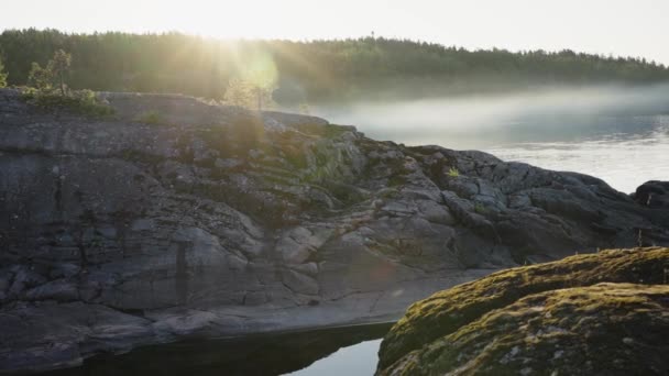 石质北岛带着苔藓 湖上一片神奇的风景 河水蒸发 阳光透过雾气平静地掠过水面 相机在移动 动作缓慢 — 图库视频影像
