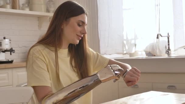 バイオニックアイアームプロテーゼを持つ笑顔の女性は 光のインテリアとキッチンで自宅で彼女の電子タッチ腕時計を押すと 医療における革新的な技術 — ストック動画