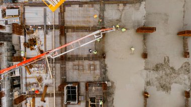 İnşaat alanının havadan görünüşü, işçiler beton döküp düzleştiriyor. Çok katlı güçlendirilmiş beton bir evin inşaatı.