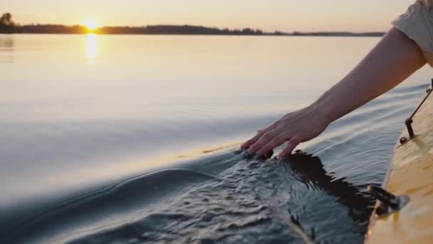 夕暮れの黄金の時間にカヤックをしながら 男は彼の手で水の表面に触れ 水を投げることによってスプラッシュを作成し 遅いアクション — ストック動画