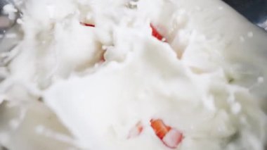 Taze çilekler ve yabanmersinleri yavaş yavaş süte karışıp sağlıklı ve lezzetli bir meyve kokteyli hazırlıyorlar.