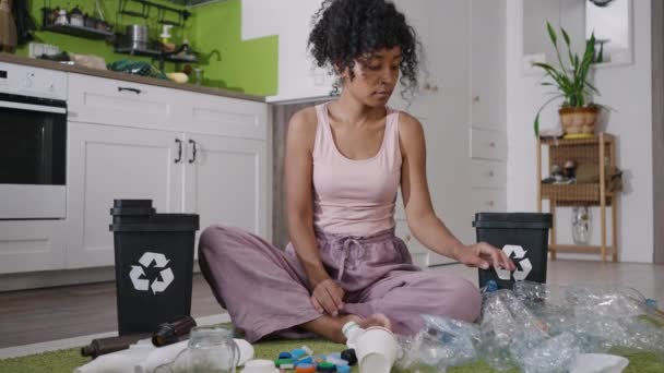 아프리카 미국인 곱슬머리의 여성은 바닥에 앉아서 쓰레기를 용기에 나누어 플라스틱 — 비디오