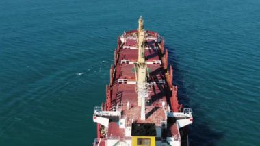 Büyük bir deniz gemisinin okyanusta büyük bir hızla ilerlemesini, güneşli havada havadan görüntüsünü takip ediyor. Uluslararası ticaret ve deniz yoluyla mal taşımacılığı