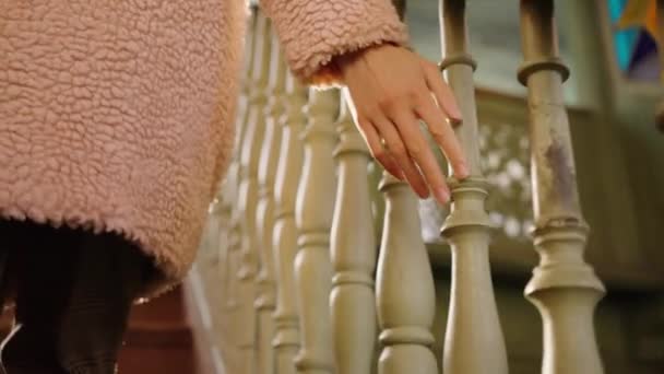 女性の豪華な毛皮のコートで彼女の手を軽く手すりの近くのバラスターのクローズアップに触れ ゆっくりと階段を登ると 過去からの思い出の概念 — ストック動画