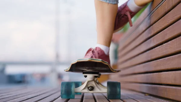 Teenage Dívka Položí Nohu Skateboard Zatímco Sedí Dřevěné Lavičce Ulici — Stock fotografie