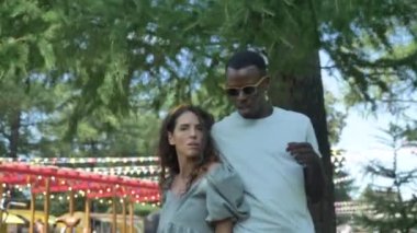Yaz mevsiminde parkta yemek kamyonları ve kurdelelerin önünde dans eden sevimli melez çift. Afrikalı Amerikalı bir adam kız arkadaşıyla dans ediyor, sosyal güvenlik kamerasında komik videolar çekiyor.