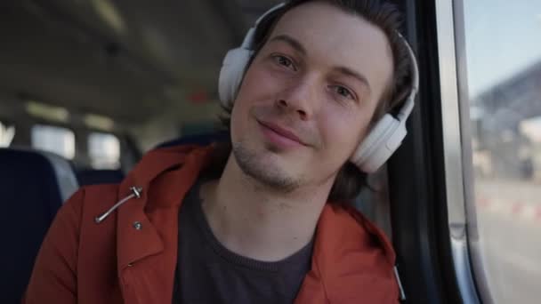 年轻的男生坐在电动车上 把头靠在窗上 用无线耳机听音乐 还拍了一张特写 — 图库视频影像