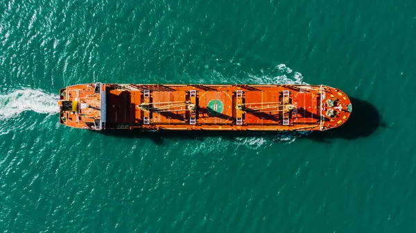 A top-down view of an oil tanker or a large cargo ship sailing on a turquoise sea. International sea transportation, transportation of fuel and cargo.