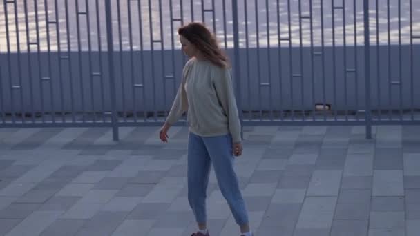 在日落时分 一个无忧无虑的年轻女子骑着滑板沿着人行道 参加极端的体育活动 — 图库视频影像