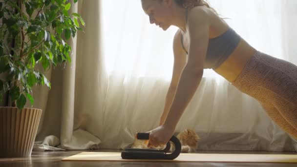 专注的女人用俯卧撑训练手臂 回到阳光充足的房间 旁边躺着一只猫 一个参加体育运动的女孩在家里的健身垫上锻炼 过着健康的生活 渴望减肥 — 图库视频影像