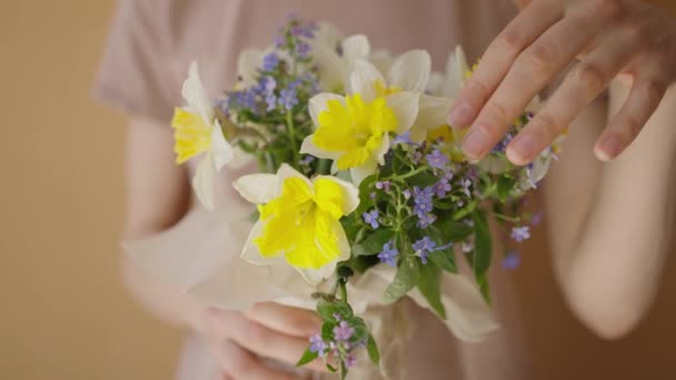 一个女人手里拿着一束亮晶晶的水仙花 仔细审视着花朵 挥动着她的手指 高兴地看着礼物 — 图库视频影像
