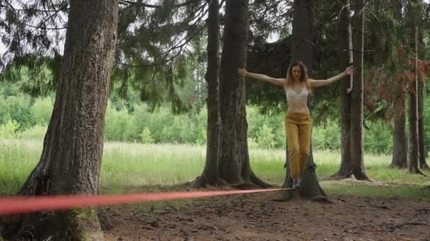 Eine Frau Läuft Vorsichtig Einer Dünnen Gespannten Linie Zwischen Bäumen — Stockvideo