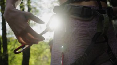 Kaya tırmanışçısı kadın kaya tırmanışı için koşum takımına hızlı çekiş yapar, güneşte yakın plan bir el. Cesur kadın dağa tırmanmaya hazırlanıyor..